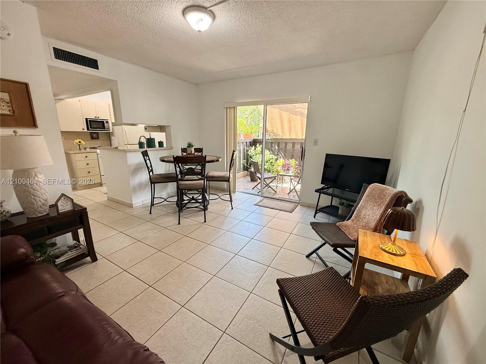 Ceramic tile flooring, pass-through kitchen window with breakfast bar, and sliding glass door with exterior patio access