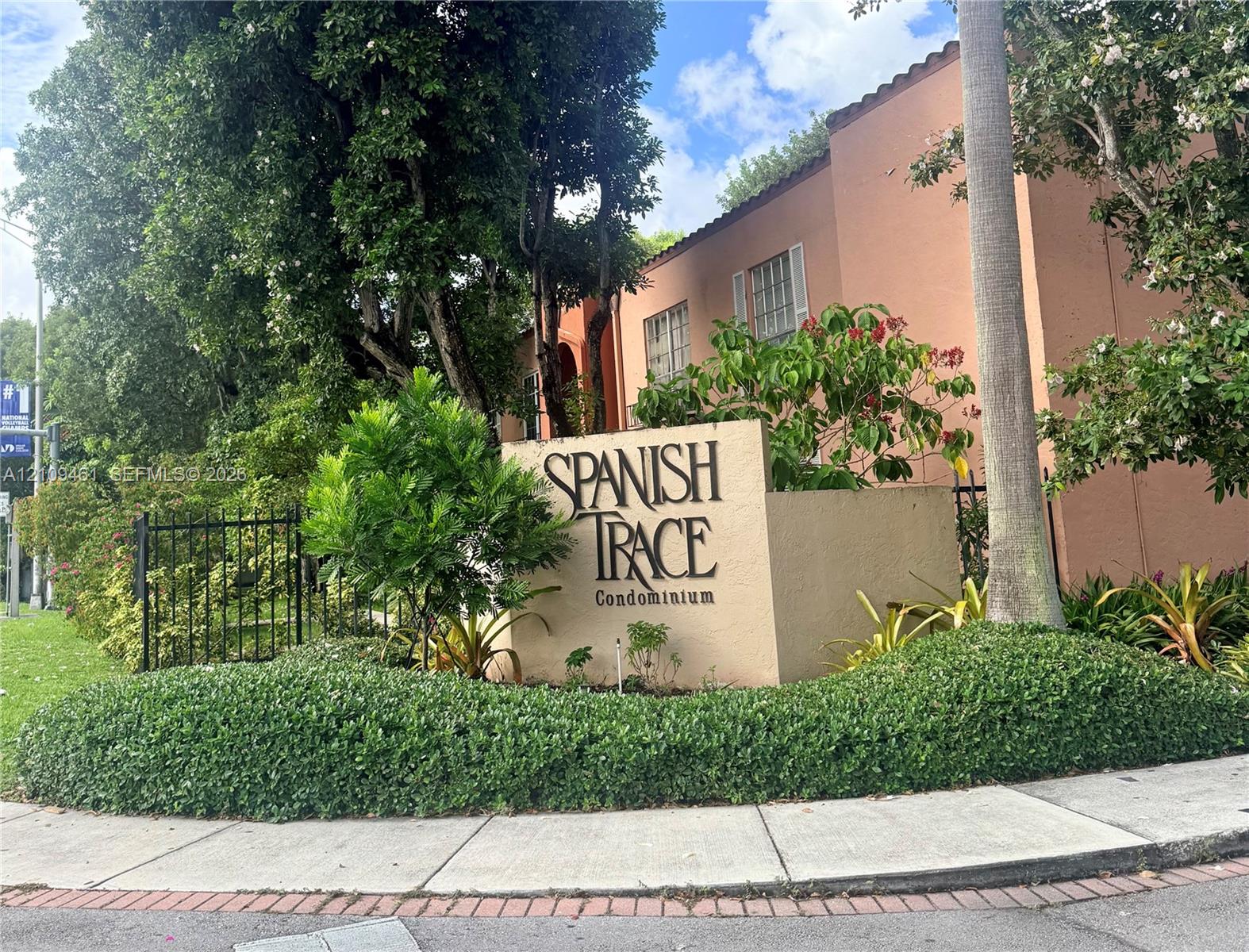 Stucco monument signage featuring professional lettering, complemented by mature landscaping, palm trees, and a decorative black iron perimeter fence Stucco monument signage featuring professional lettering, complemented by mature landscaping, palm trees, and a decorative black iron perimeter fence