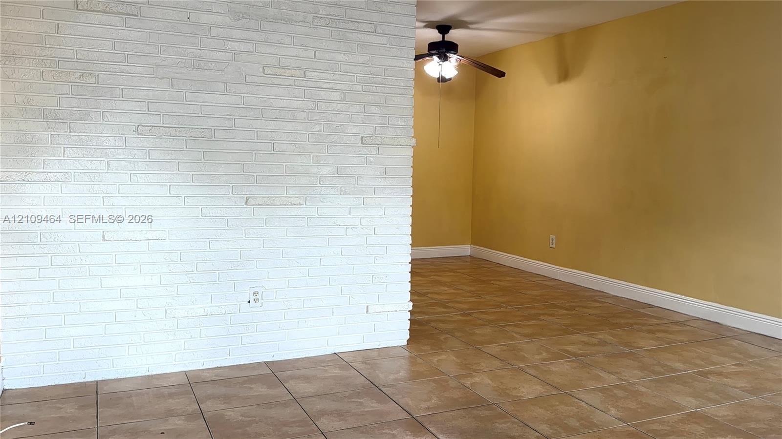 White painted masonry accent wall, neutral ceramic tile flooring, and ceiling-mounted light fixture