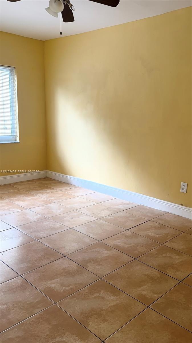 Room featuring large-format tile flooring and a ceiling-mounted light fixture with a fan