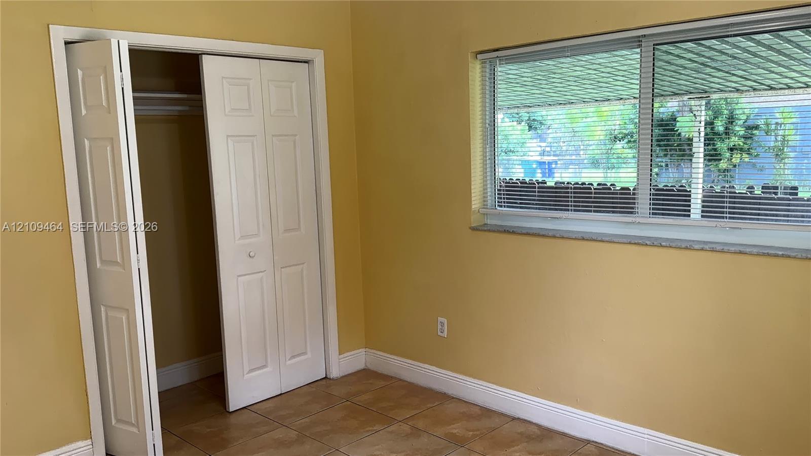 Room featuring large-format ceramic tile flooring, a horizontal sliding window with a stone sill, and a closet with bifold doors