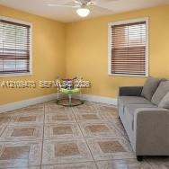 Interior space featuring ceramic tile flooring, two windows with horizontal blinds, and a white ceiling fan with integrated lighting Interior space featuring ceramic tile flooring, two windows with horizontal blinds, and a white ceiling fan with integrated lighting