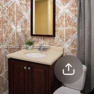 Dark-finish vanity cabinet, solid-surface countertop with integrated oval basin, polished chrome faucet, framed mirror, and decorative wall tiling Dark-finish vanity cabinet, solid-surface countertop with integrated oval basin, polished chrome faucet, framed mirror, and decorative wall tiling
