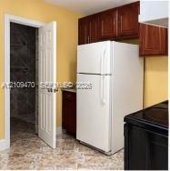 Dark-toned cabinetry, white refrigerator, black range, and patterned stone-style flooring Dark-toned cabinetry, white refrigerator, black range, and patterned stone-style flooring