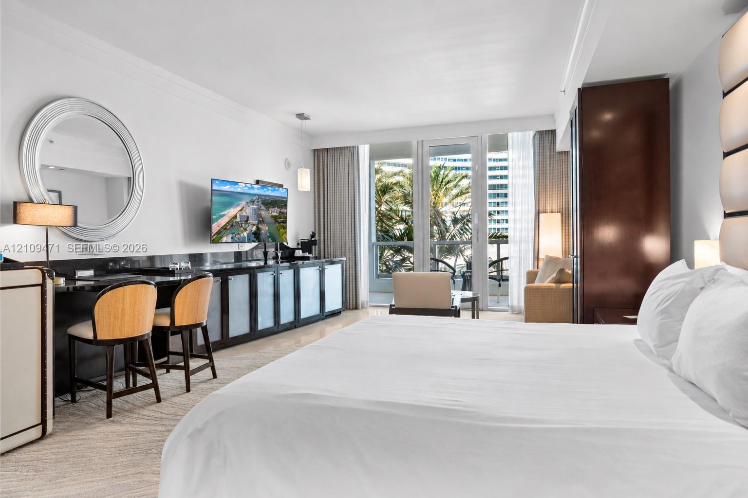 Custom built-in cabinetry with stone-finish surfaces, circular wall mirror, integrated lighting, and glass-paneled exterior door Custom built-in cabinetry with stone-finish surfaces, circular wall mirror, integrated lighting, and glass-paneled exterior door