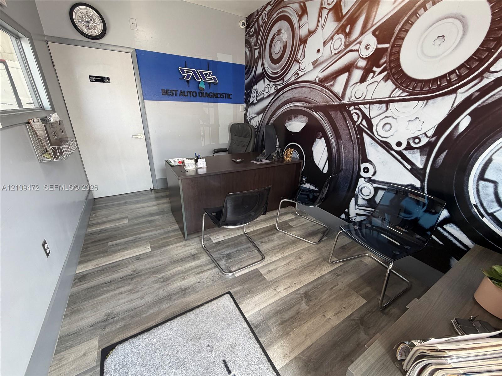Interior office space featuring wood-finish flooring, a wall-length graphic mural, and a crisp white door