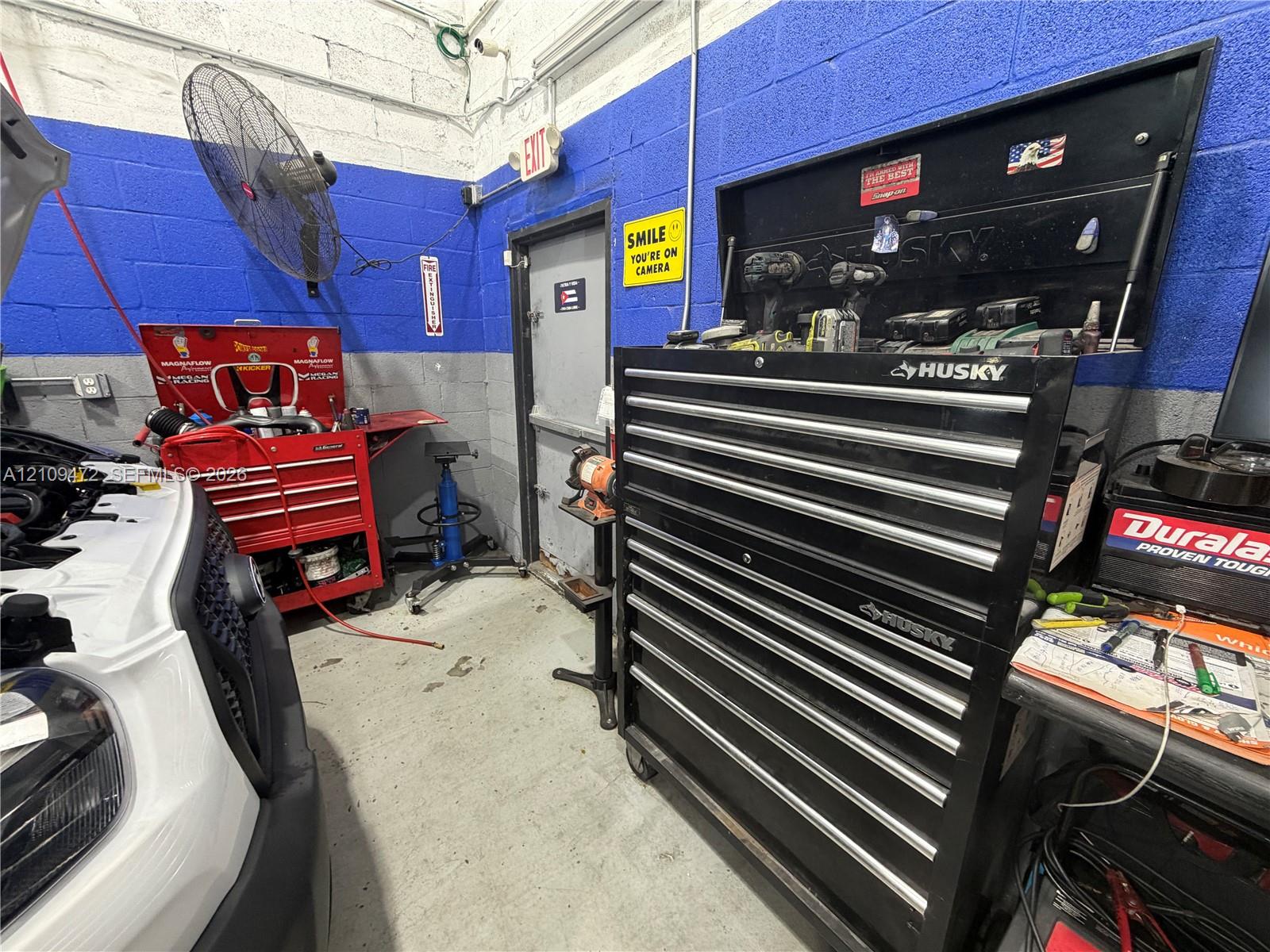 Concrete flooring, painted masonry walls, and wall-mounted industrial fan