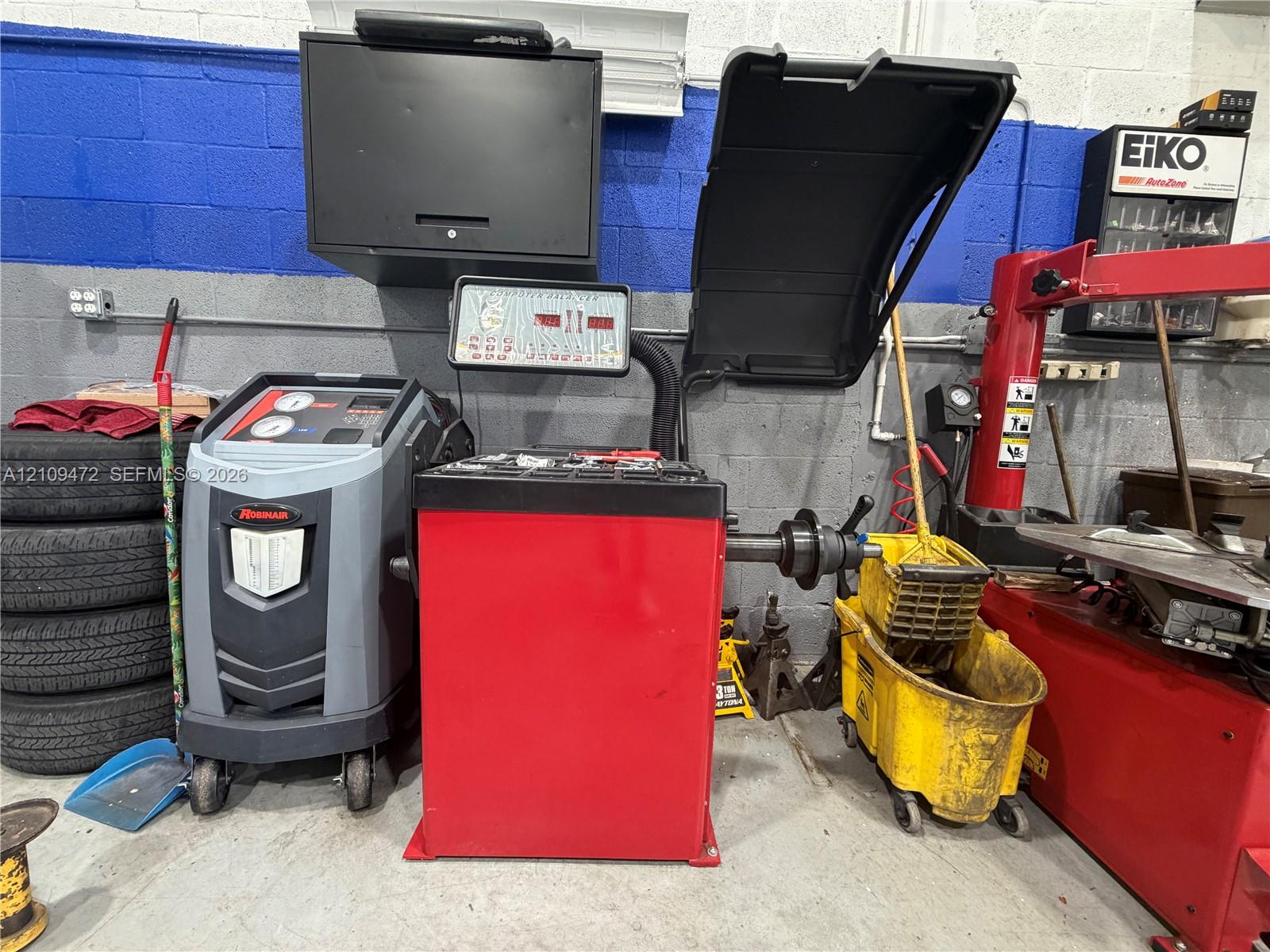 Professional-grade automotive equipment featuring a digital tire balancer with red steel casing, a wheel service machine, and mounted diagnostic console
