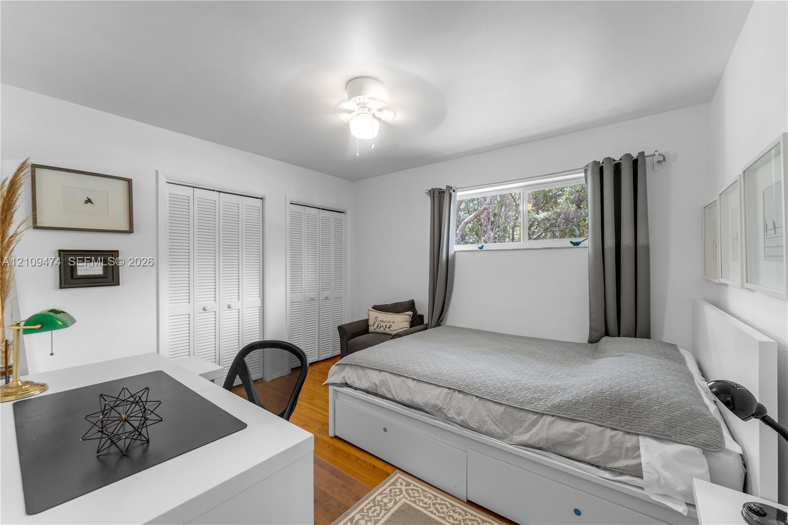 Hardwood flooring, dual louvered-panel closets, and a ceiling-mounted light fixture with integrated fan