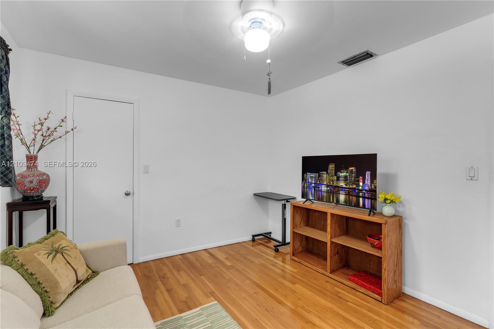 Room featuring wood-finish flooring and a central ceiling fan with integrated lighting