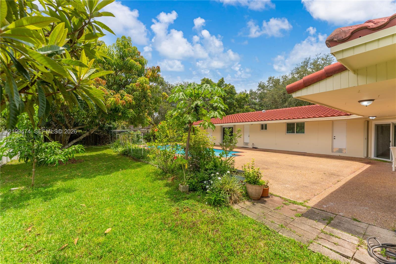 Rear exterior featuring a swimming pool, covered patio with aggregate flooring, and red tile roofing