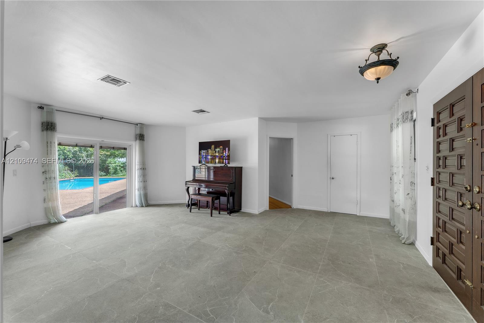 Interior space featuring large-format tile flooring, a custom solid wood multi-panel entry door, recessed lighting, and a sliding glass door providing external access
