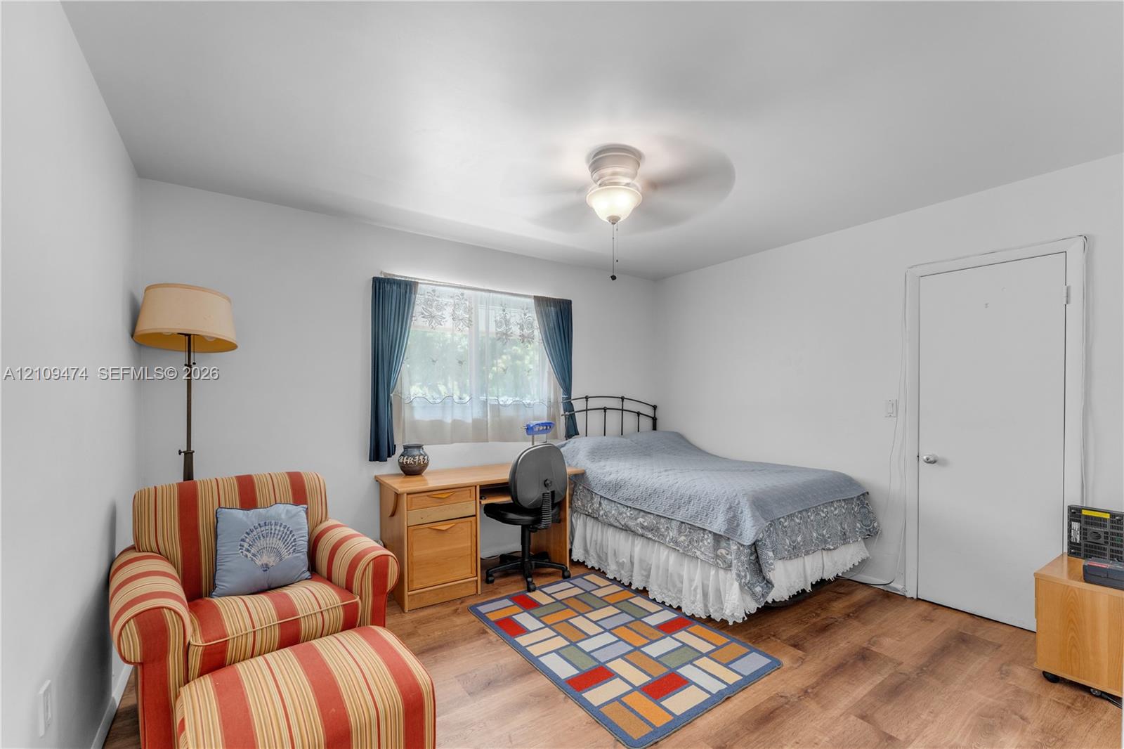 Room featuring wood-finish flooring, a ceiling fan with integrated lighting, and a single-pane window
