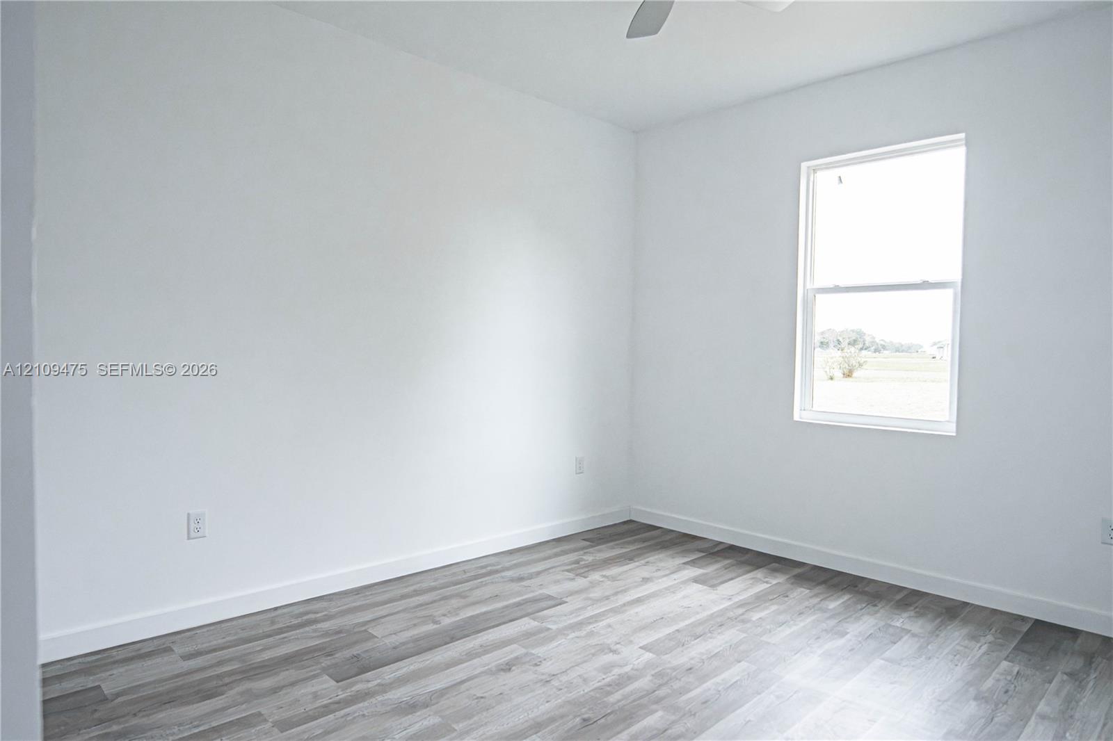 Room with neutral walls, wood-finish flooring, single-hung window, and overhead ceiling fan