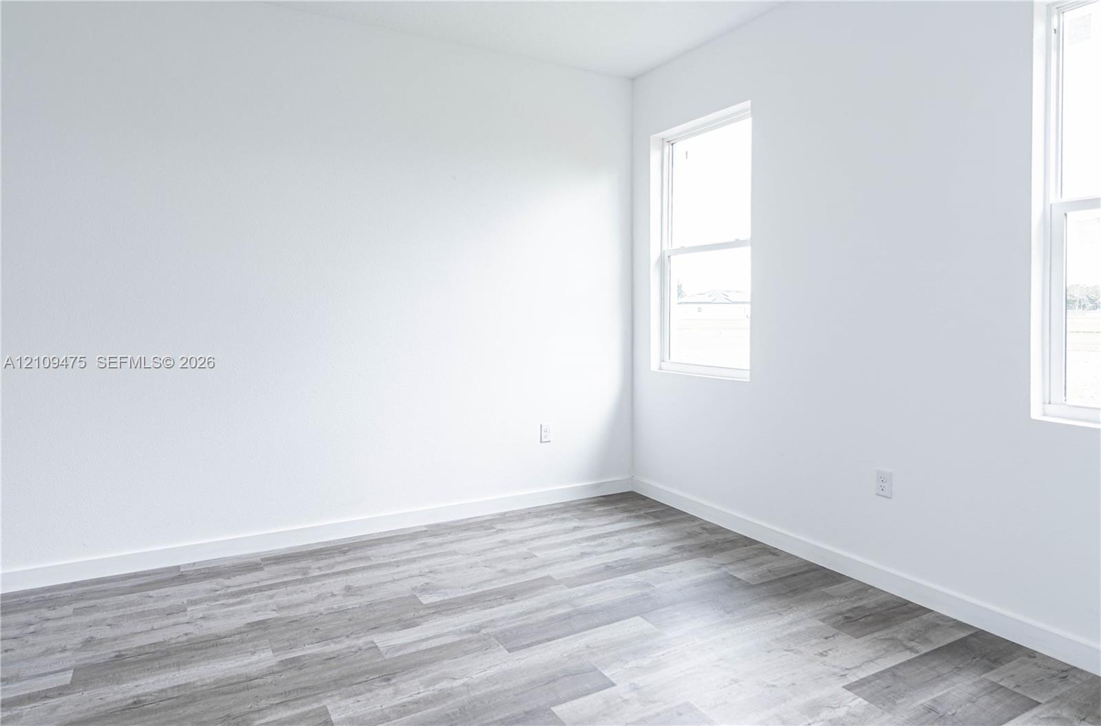 Neutral-toned interior space featuring wood-finish flooring and dual double-hung windows