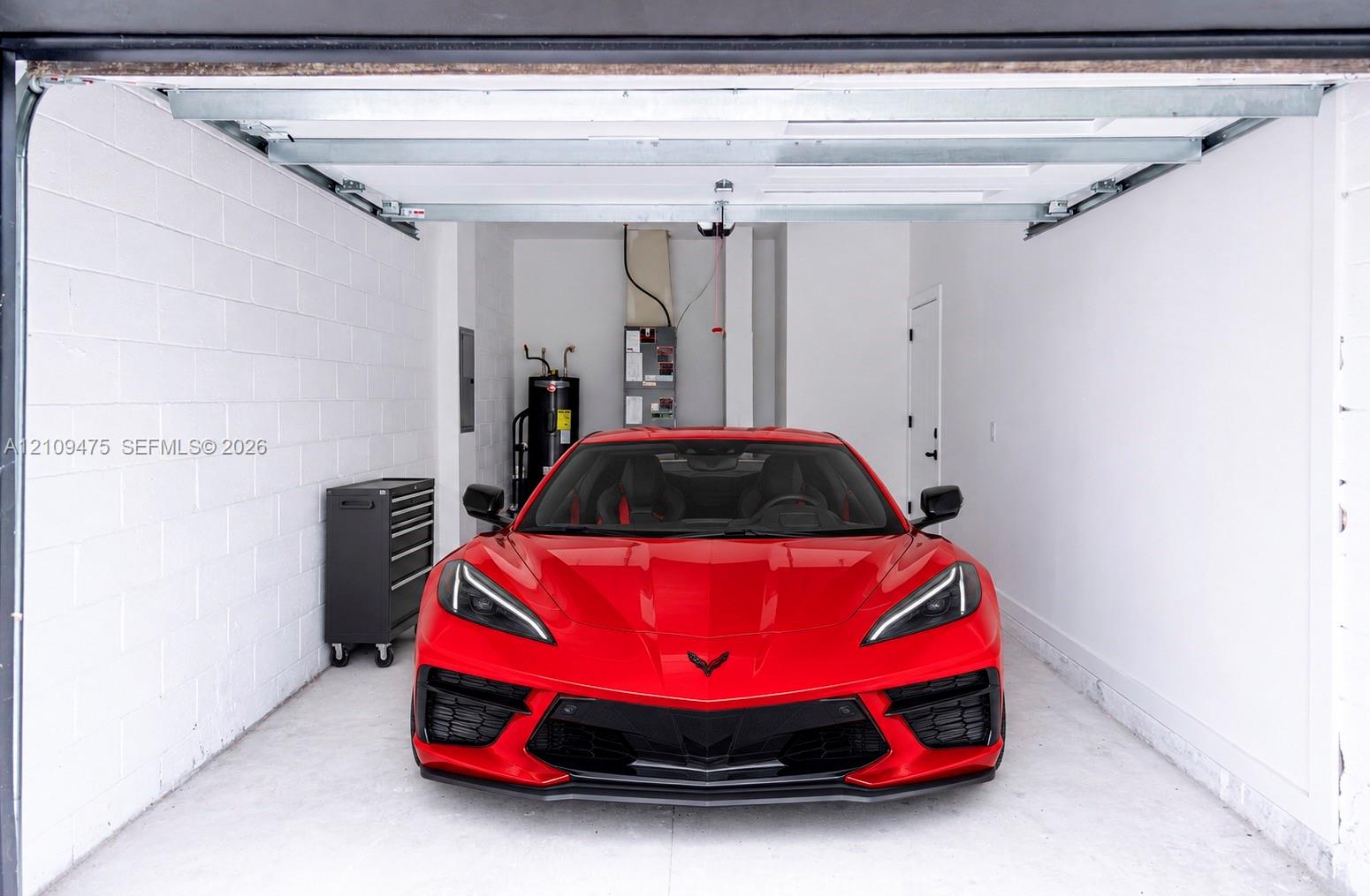 Enclosed garage featuring painted concrete block walls, overhead sectional door, and dedicated utility area