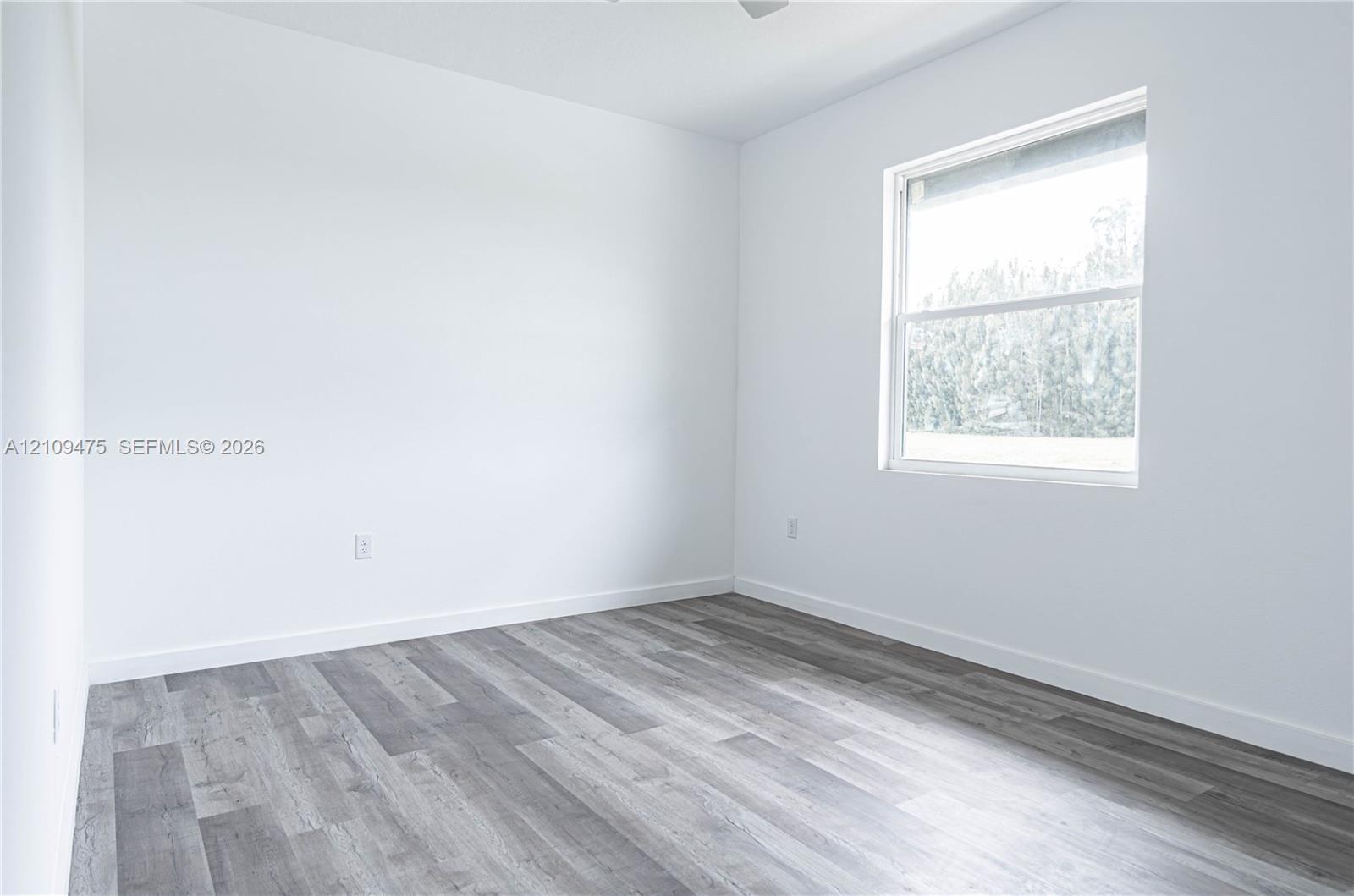 Interior space featuring wood-finish flooring, white walls, and a single-pane window