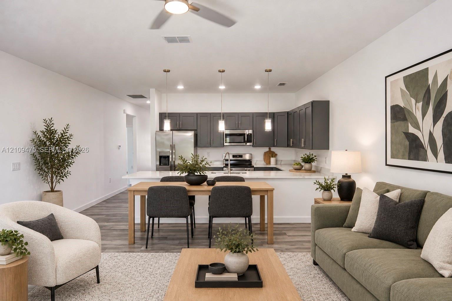 Kitchen featuring dark cabinetry, quartz countertops, stainless steel appliances, a peninsula, and wood-finish flooring