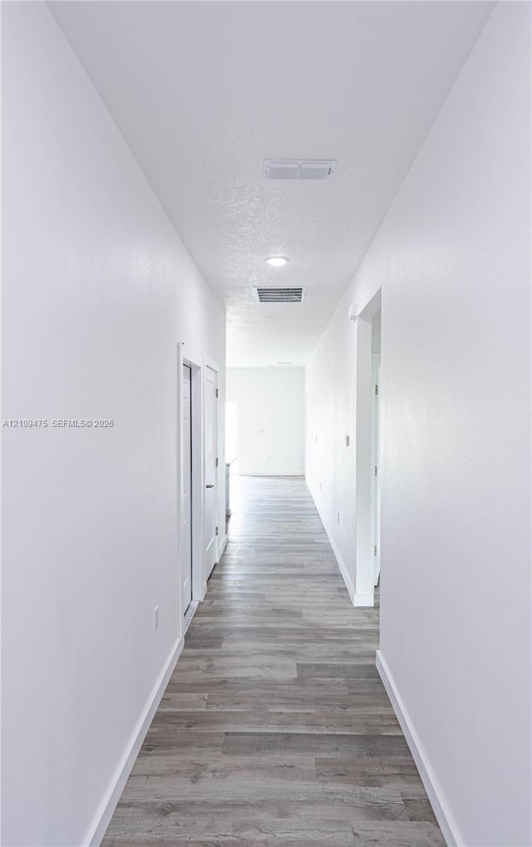 Hallway featuring wood-finish flooring, recessed lighting, and crisp white wall finishes