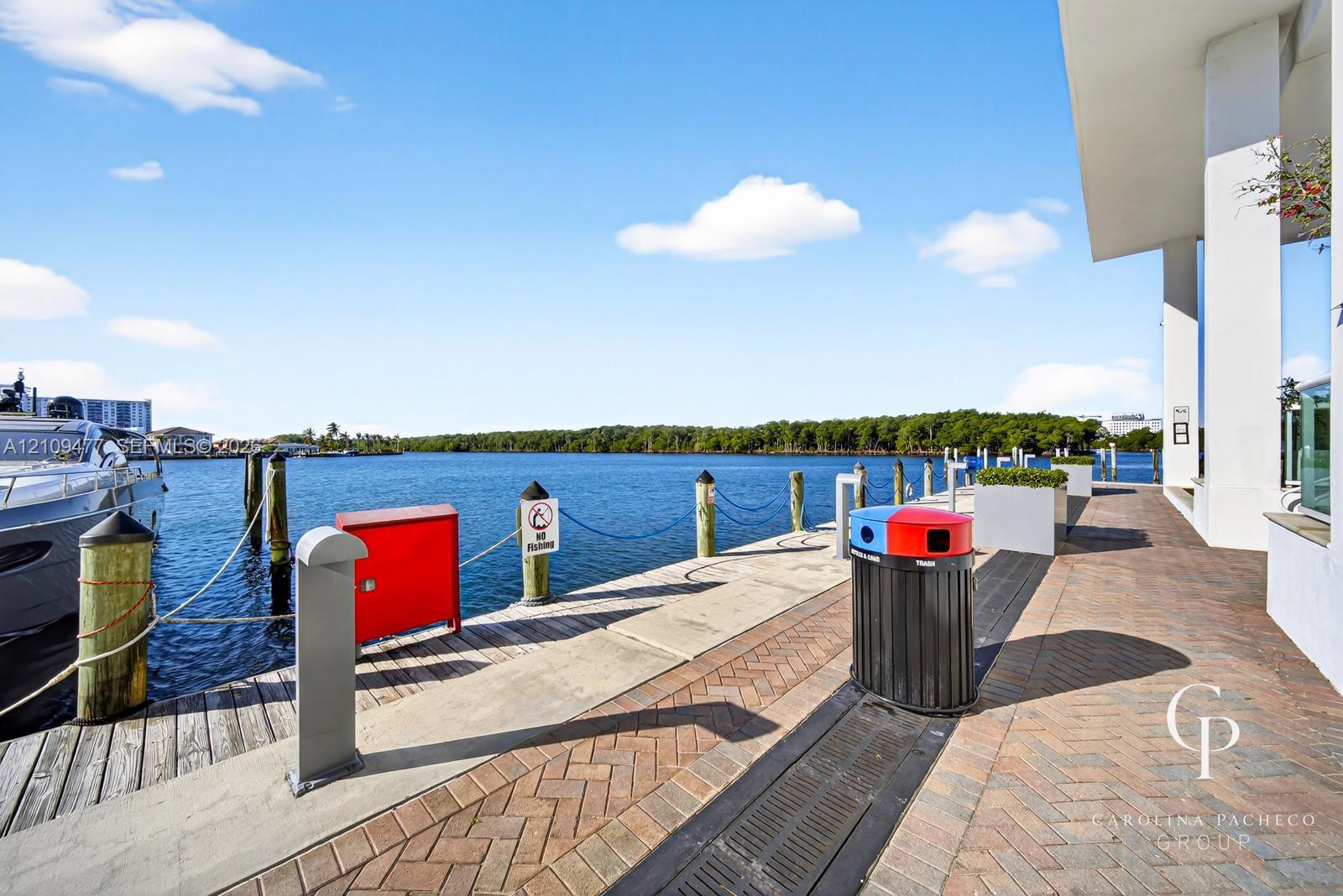 Waterfront bulkhead featuring herringbone-patterned brick pavers, concrete pier edging, and wood pilings
