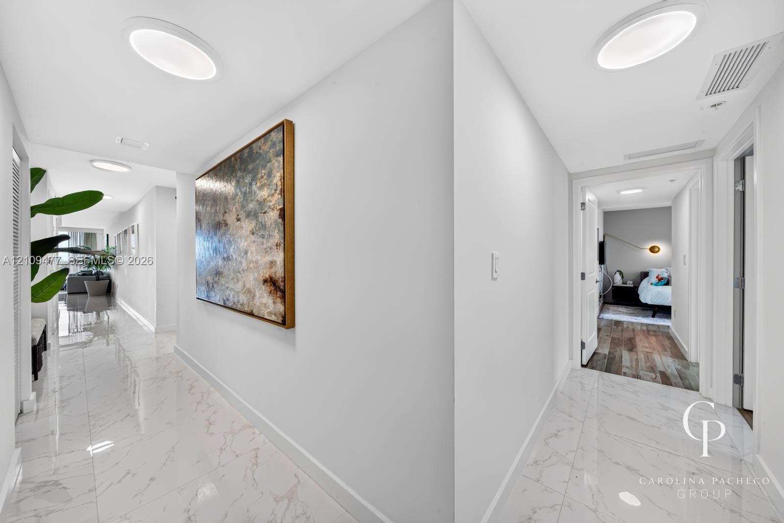 Hallway featuring polished stone-finish tile flooring, recessed LED ceiling lighting, and crisp white wall finishes