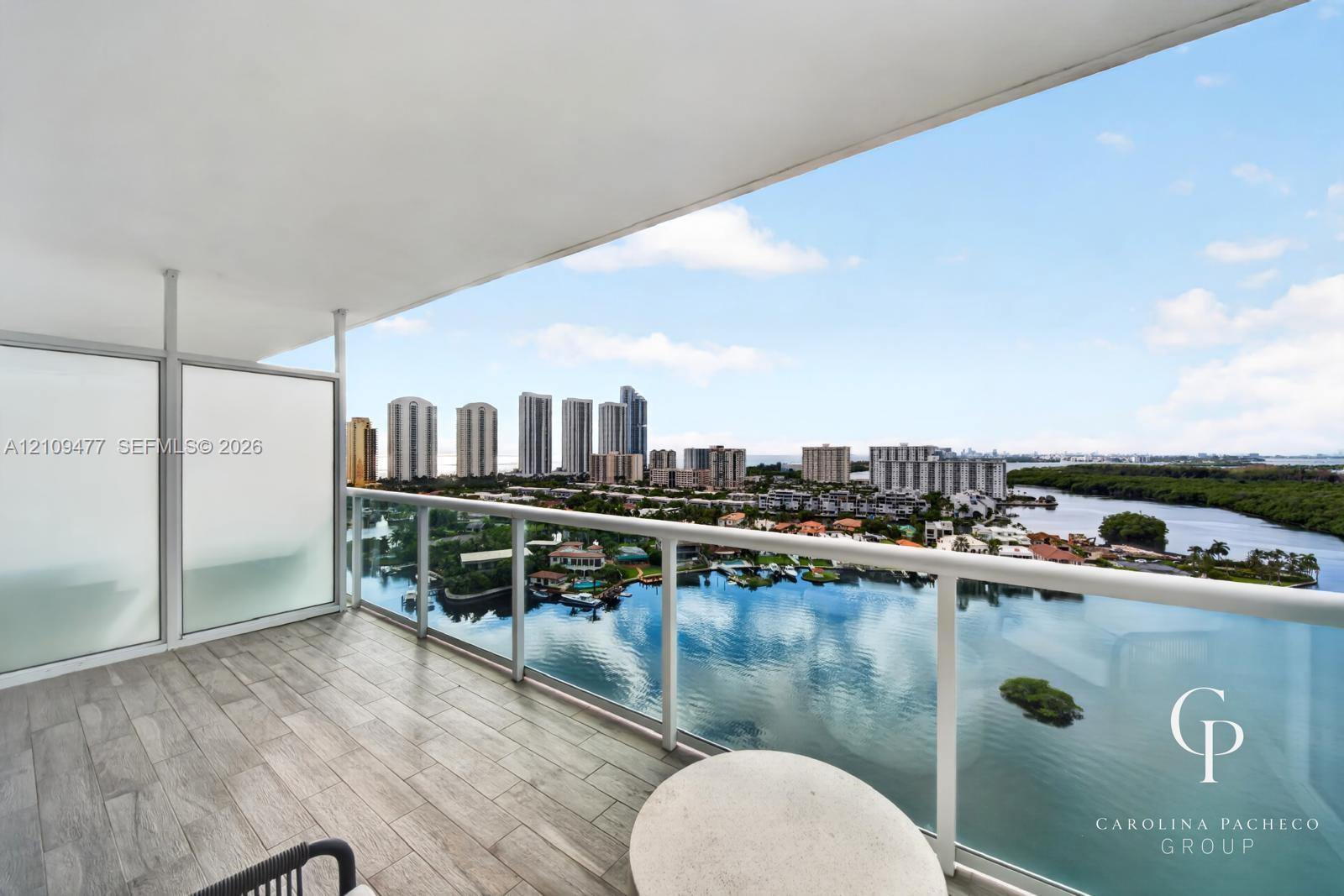 Covered balcony featuring wood-finish tile flooring, glass panel railing, and frosted privacy screens