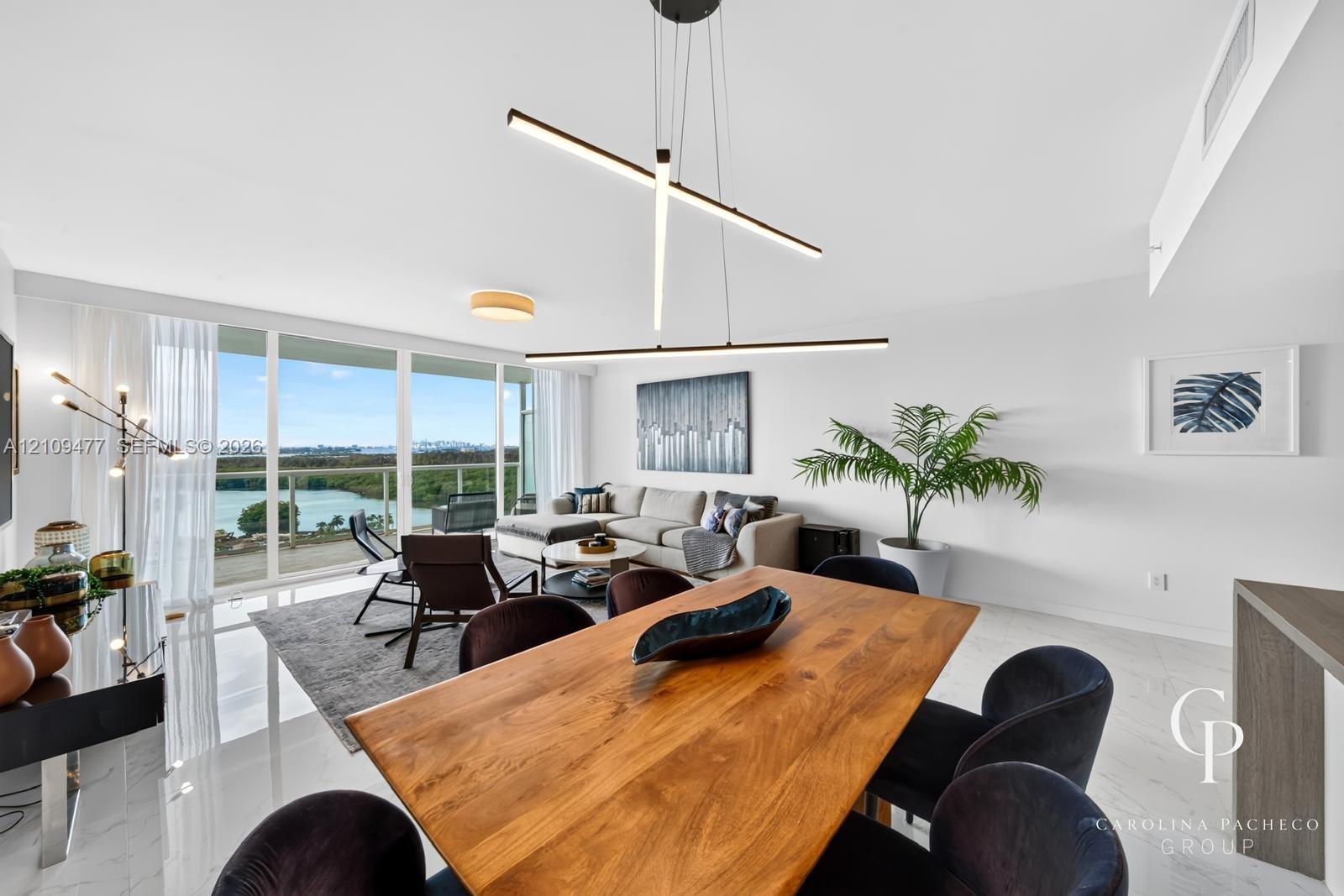 Open-concept space featuring floor-to-ceiling windows, white polished tile flooring, contemporary linear LED pendant lighting, and a glass-railed balcony