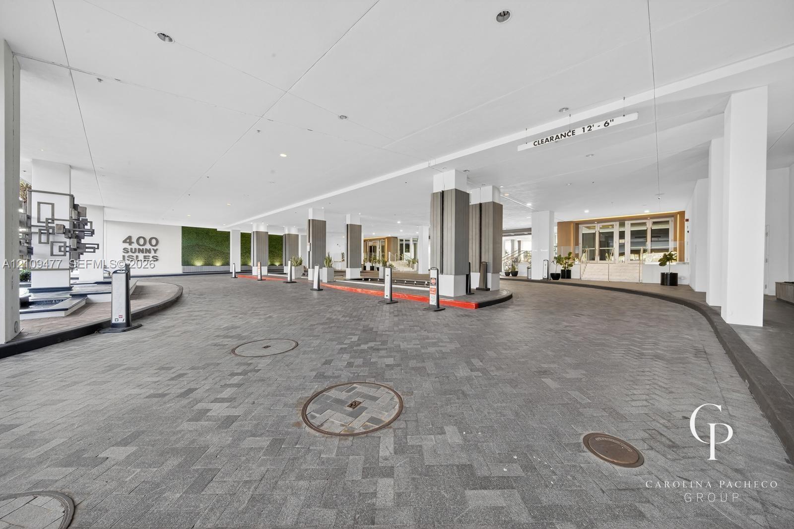 Covered porte-cochre featuring a herringbone-patterned stone driveway, recessed lighting, integrated vertical accent columns, and a decorative living green wall