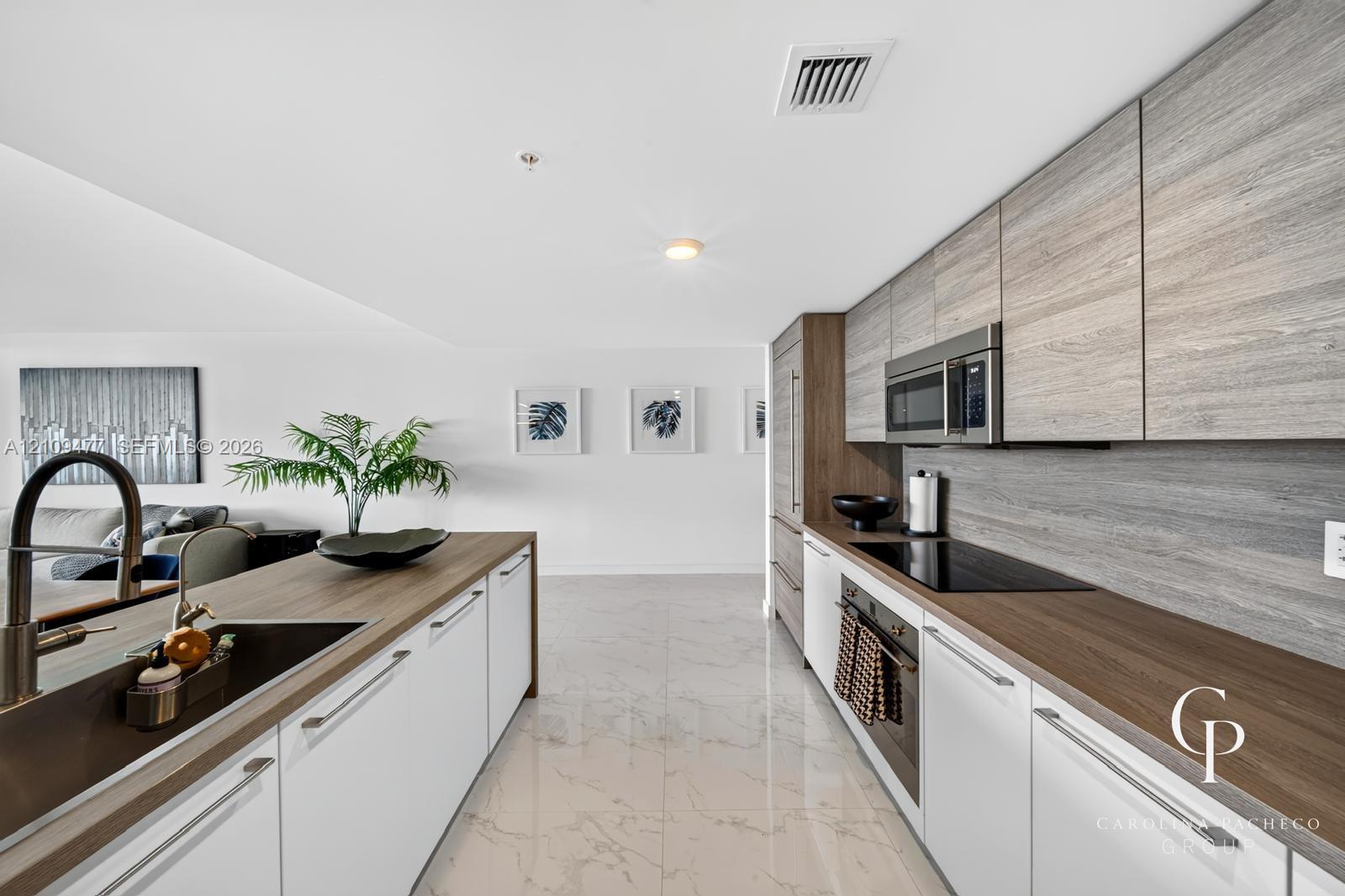 Kitchen featuring flat-panel cabinetry with wood-grain finish, polished stone-finish flooring, integrated appliances, and wood-finish countertops