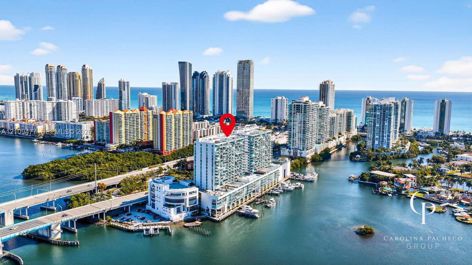 Aerial perspective of a high-rise residential building situated on the waterfront, featuring a private marina and balconies with glass railings