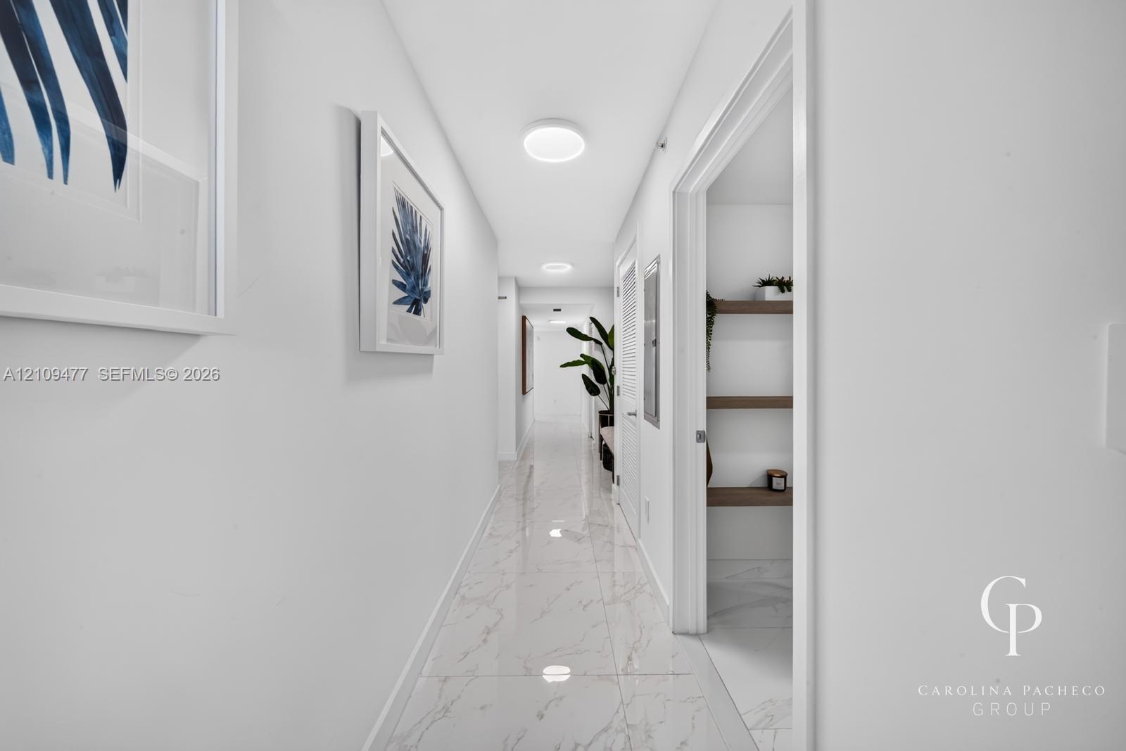 Hallway featuring polished tile flooring, recessed LED lighting, and a storage closet with built-in wooden shelving