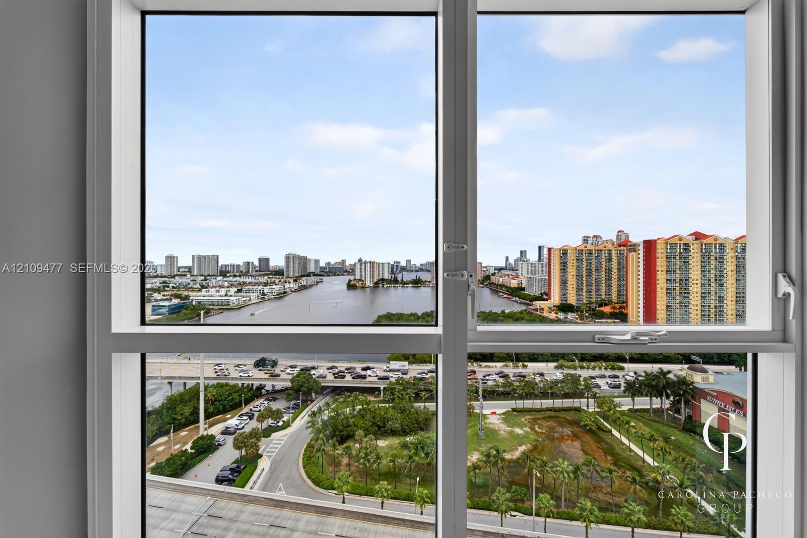 Oversized picture windows with white frames featuring panoramic exposure of the waterway, urban skyline, and surrounding landscape