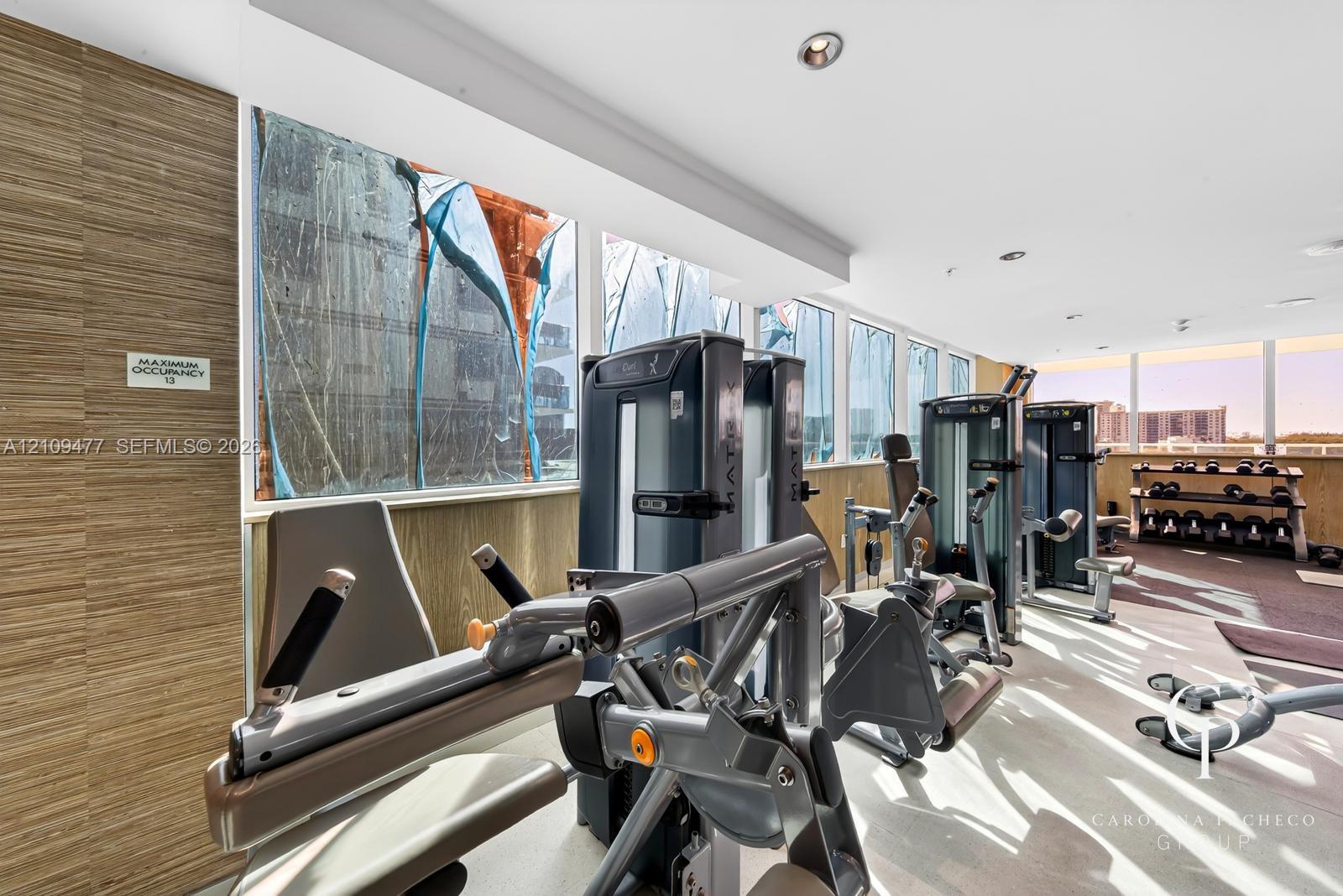 Fitness center featuring floor-to-ceiling windows, wood-finish wall paneling, and recessed lighting