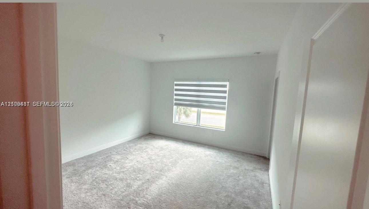 Interior room featuring neutral wall paint, plush carpeting, and a window with installed roller shades