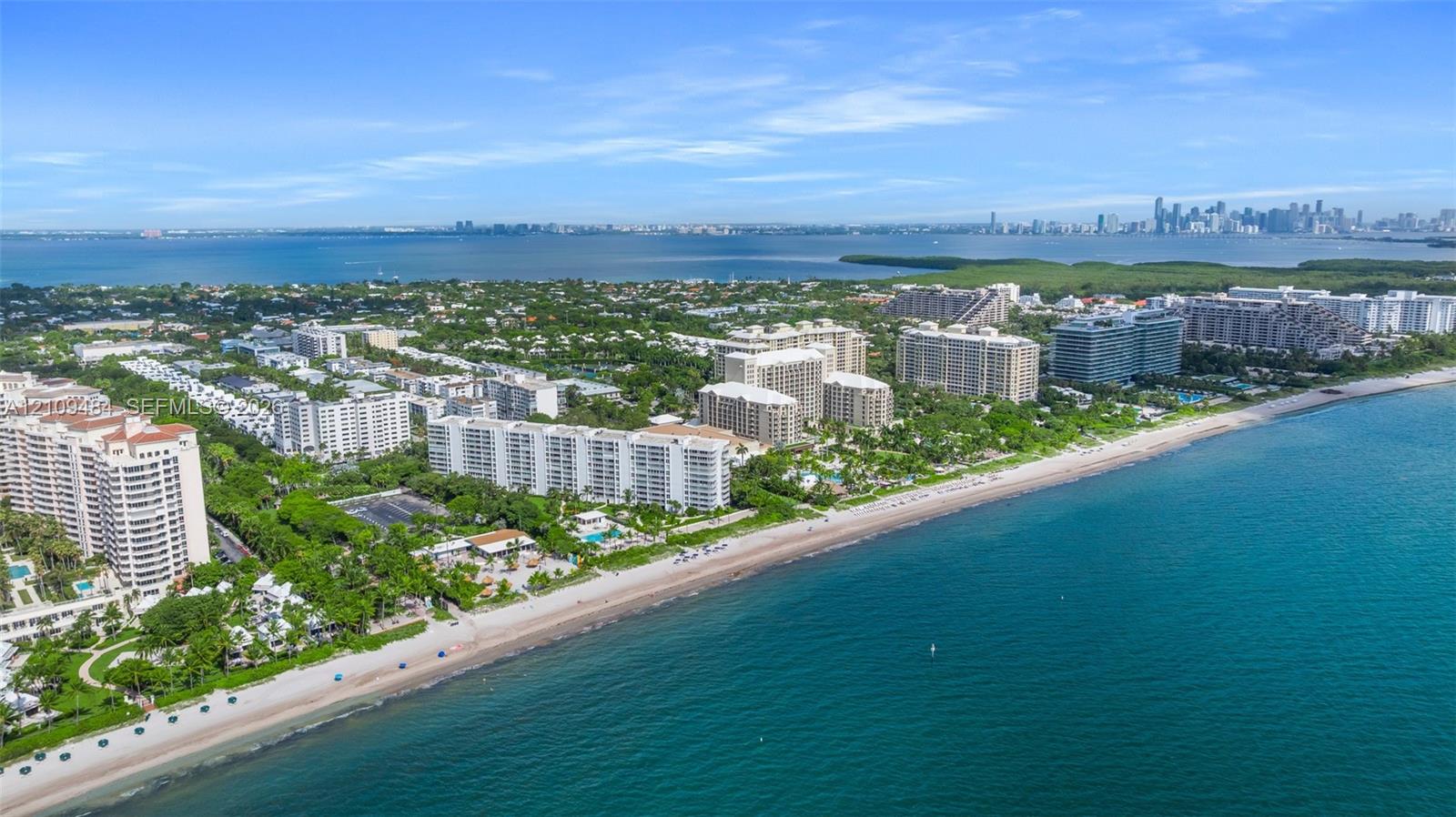 Aerial perspective featuring direct oceanfront access, coastal shoreline, and high-rise residential architecture with proximity to the metropolitan skyline