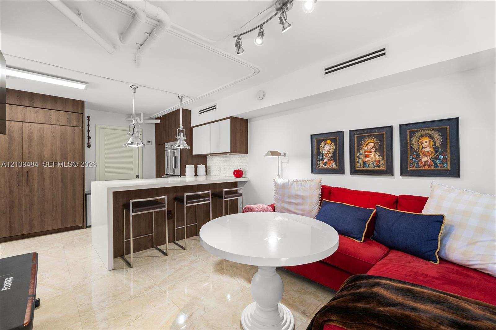 Kitchen area featuring a peninsula with a waterfall-edge stone countertop, wood-finish cabinetry, built-in stainless steel oven, and polished stone flooring