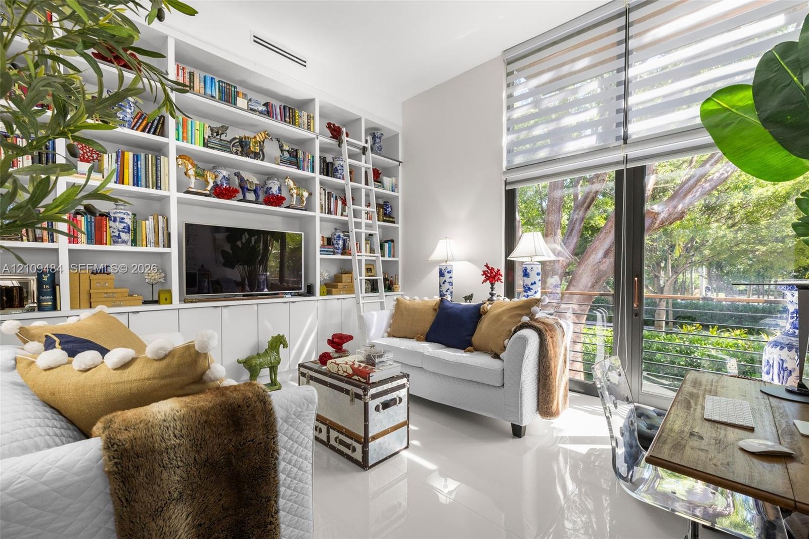 Full-height custom built-in cabinetry featuring integrated shelving, a rolling library ladder, and lower closed storage cabinets Full-height custom built-in cabinetry featuring integrated shelving, a rolling library ladder, and lower closed storage cabinets