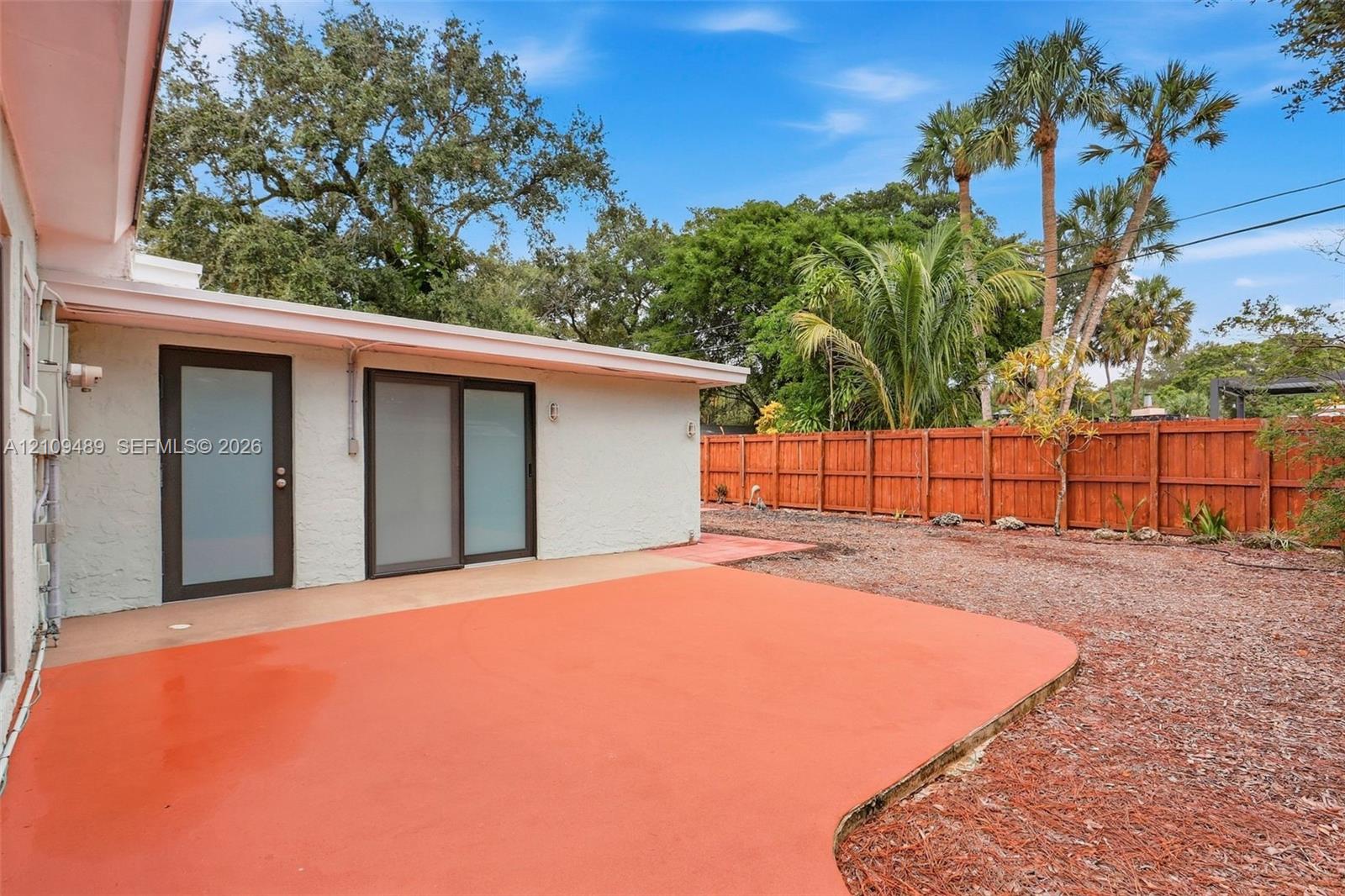 Stucco exterior featuring a stained concrete patio, frosted glass door, sliding glass door, and wooden privacy fencing