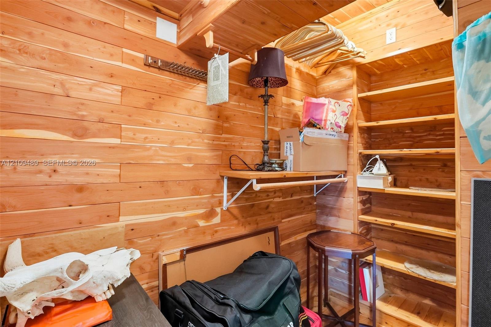 Storage space featuring natural wood-plank wall paneling, built-in wooden shelving, and fixed wooden hanging rods