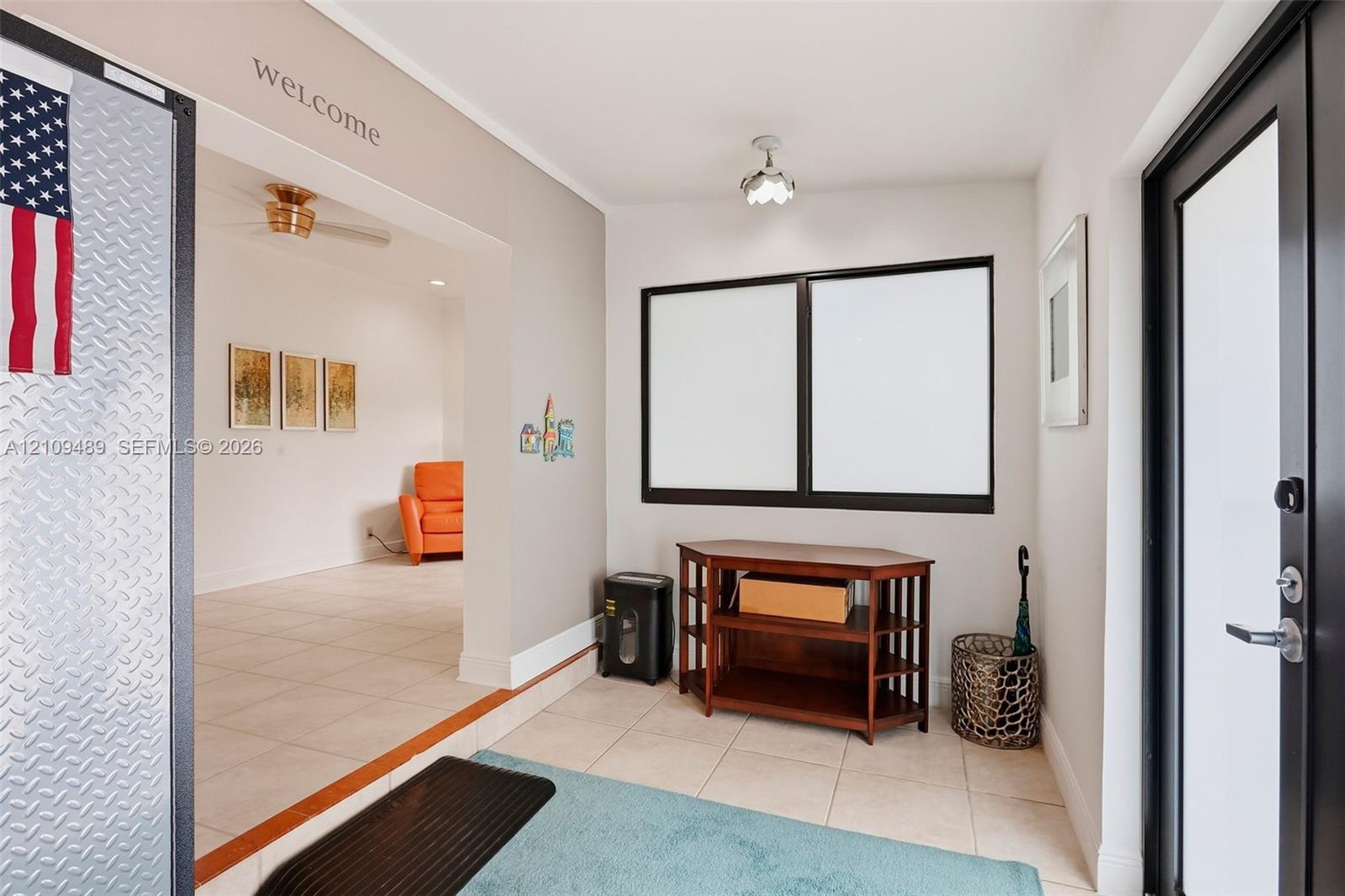 Entryway featuring large-format tile flooring, dual-pane windows with dark frames, and a glass-inset exterior door with metallic hardware
