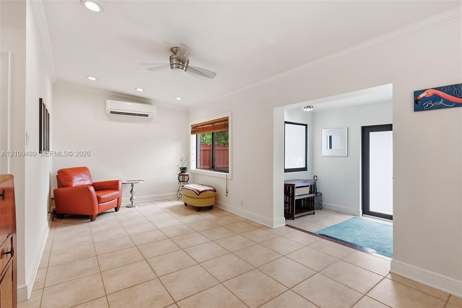 Neutral ceramic tile flooring, ceiling fan, wall-mounted climate control unit, recessed lighting, and crown molding