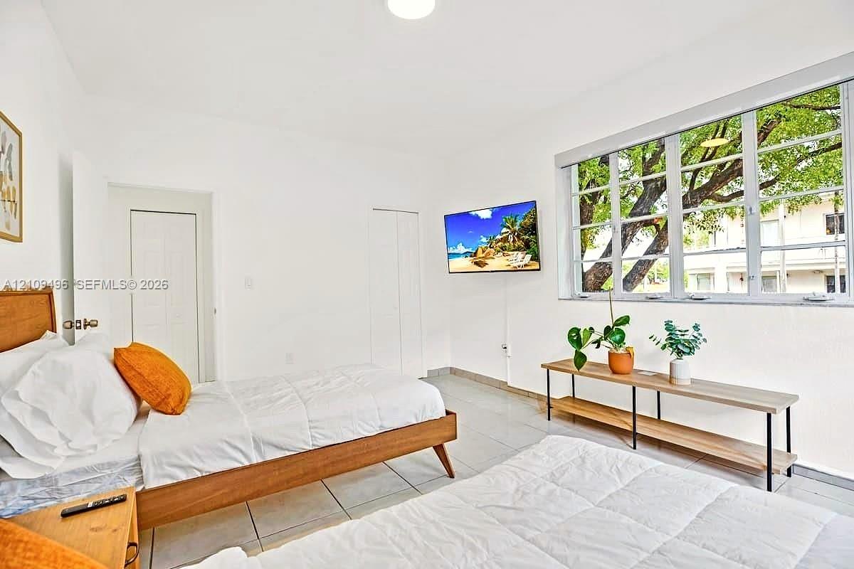 Neutral interior featuring white walls, large multi-pane windows with horizontal muntins, and light-toned ceramic tile flooring