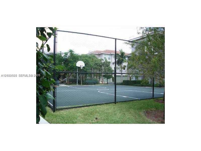 Fenced sports court featuring a painted hard surface, integrated basketball hoop, and perimeter chain-link enclosure