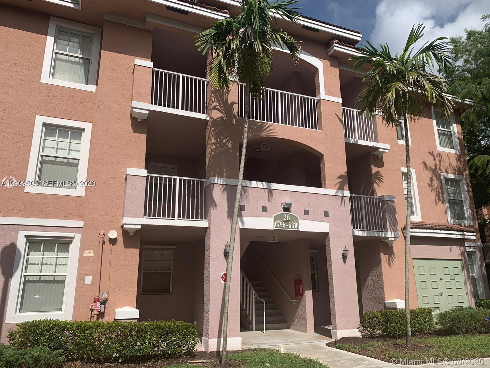 Stucco exterior featuring multi-level balconies with metal railings, arched architectural details, and mature palm landscaping