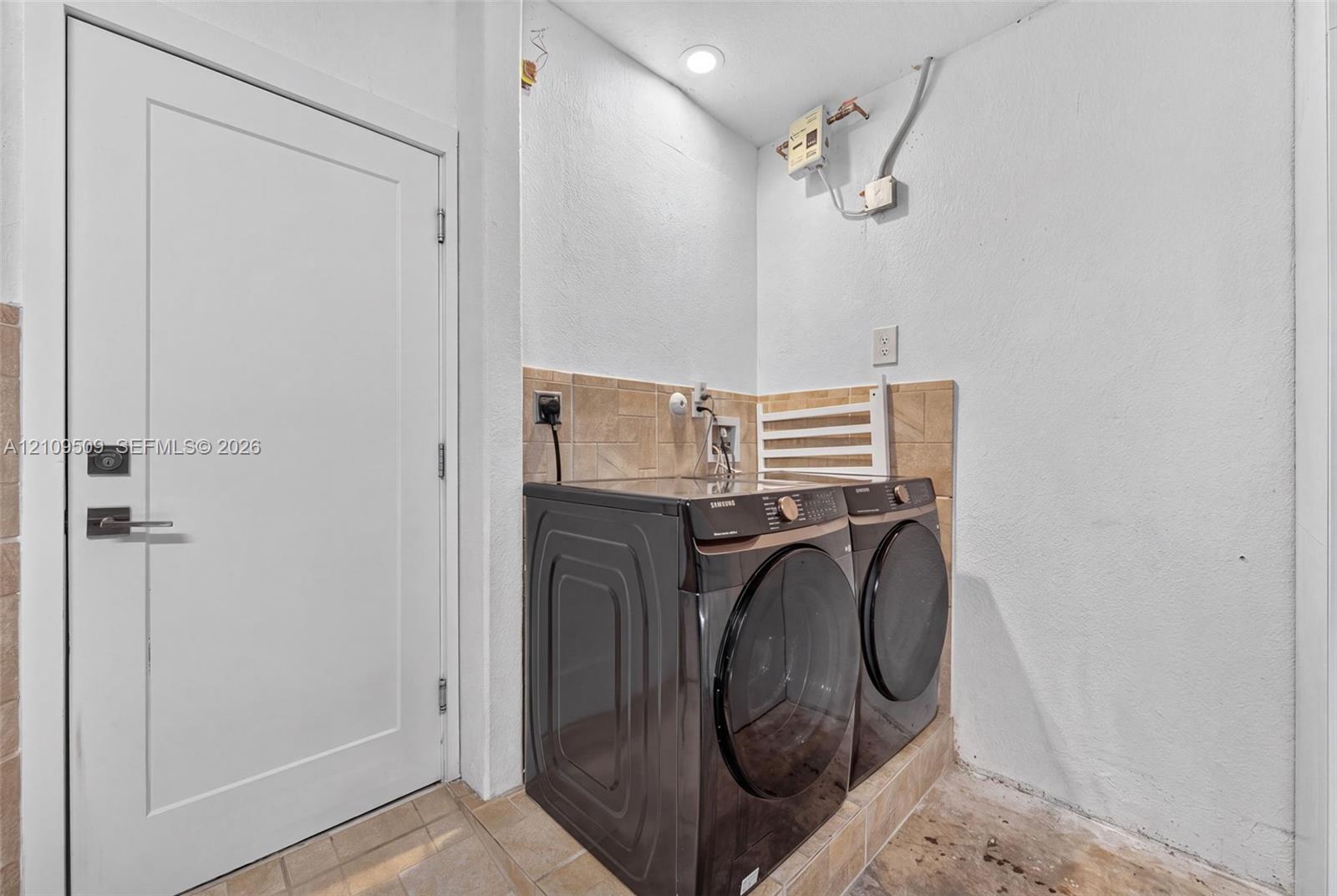 Laundry area featuring a tile backsplash, recessed ceiling lighting, and a solid-core interior door with brushed metal hardware