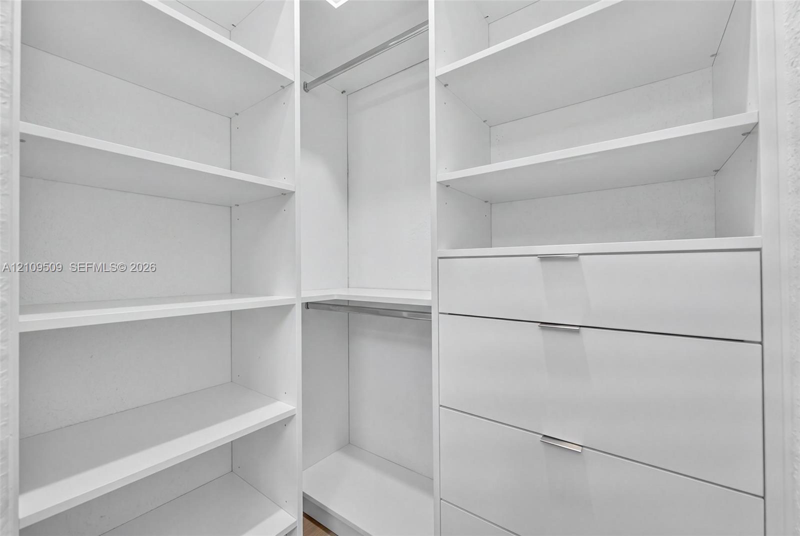 Custom built-in storage featuring white cabinetry, multiple open shelving units, integrated clothing rods, and soft-close drawers with minimalist hardware