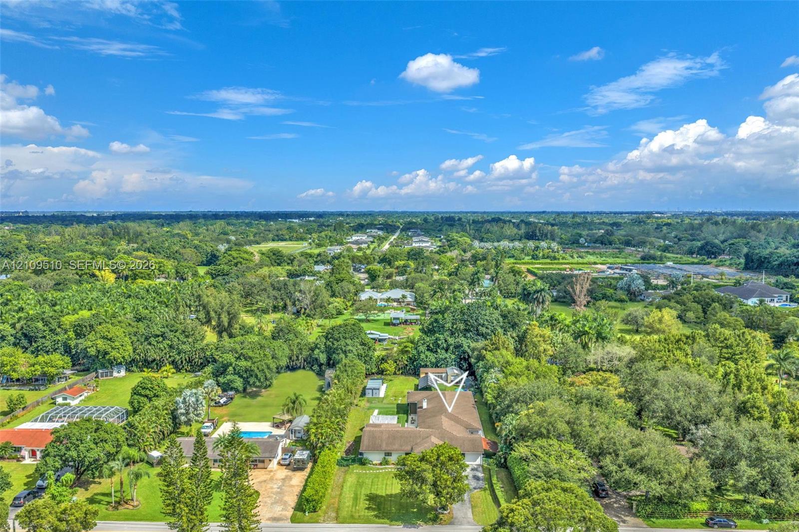Aerial perspective featuring a multi-pitched shingle roof, expansive manicured grounds, and mature perimeter landscaping