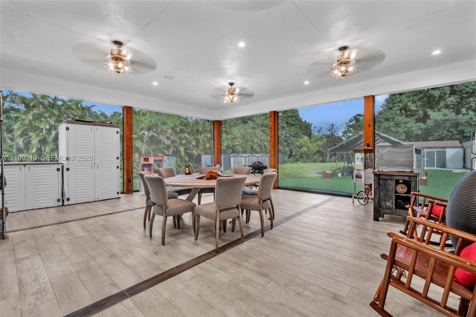 Screened patio featuring wood-finish tile flooring, recessed lighting, and triple ceiling fans with integrated light fixtures