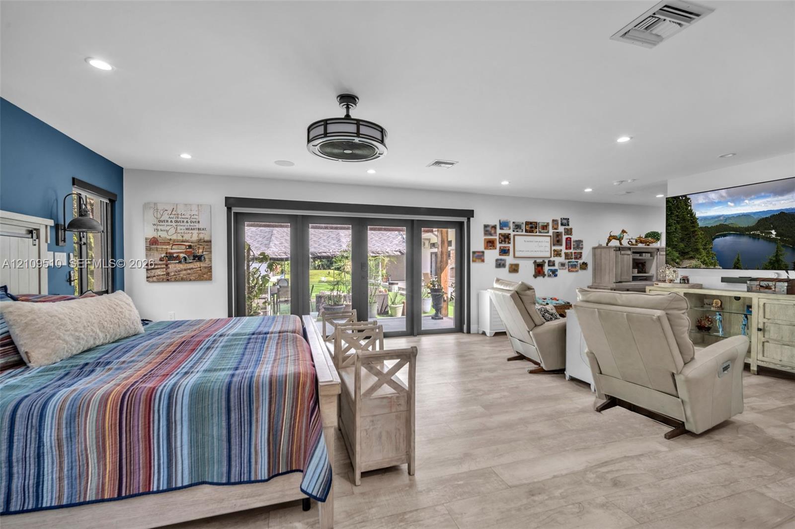 Wood-finish flooring, multi-panel sliding glass doors, recessed lighting, and a drum-style ceiling fan with an integrated light fixture