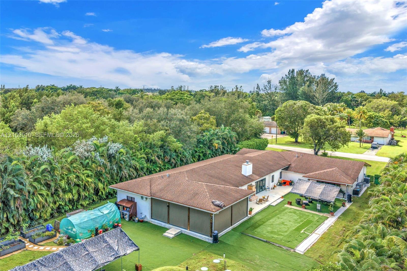 Expansive backyard featuring artificial turf, a masonry chimney, and perimeter landscaping